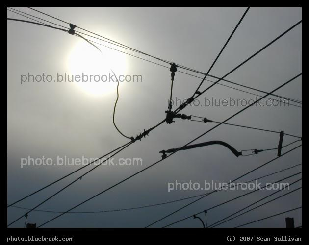 Subway Wires - Overhead electrical wires, for the MBTA Green Line, silhouetted against the sun at Reservoir Station, Boston MA