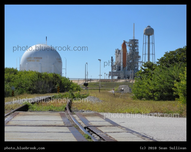 Hydrogen Supply - Space shuttle Discovery on Kennedy Space Center launch pad 39-A, with a liquid hydrogen fuel storage tank in the foreground, seen from Beach Road.