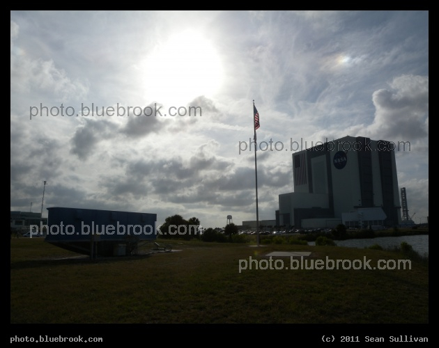 Clouds over Press Site - The sun and clouds over the Kennedy Space Center press site, with the back side of the countdown clock (left) and nearby Vehicle Assembly Building (right), shortly after the launch of Atlantis on flight STS-132