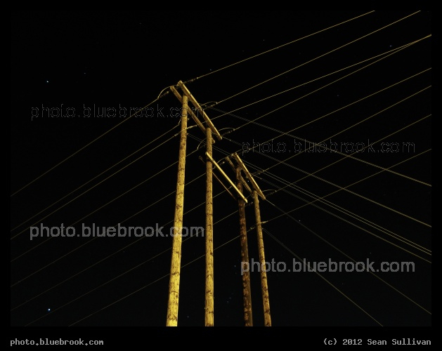 Poles, Wires and Stars - Overhead wires on the north shore of a crossing of the Merrimack River, with stars in the background (Orion is directly behind the telegraph poles, with the nebula visible between the middle poles).  Haverhill, MA