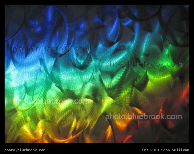 Rainbow Swirls - A sunbeam broken into the colors of the rainbow falling upon a silver surface in the lobby of MBTA Courthouse Station, Boston MA